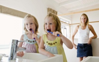 Mother and twin girls brushing teeth